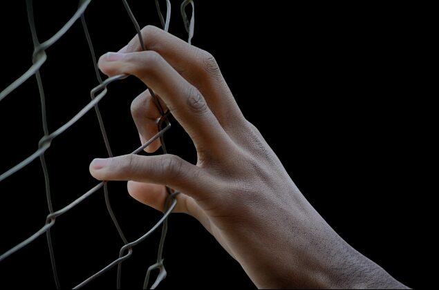 Hand gripping a wire fence
